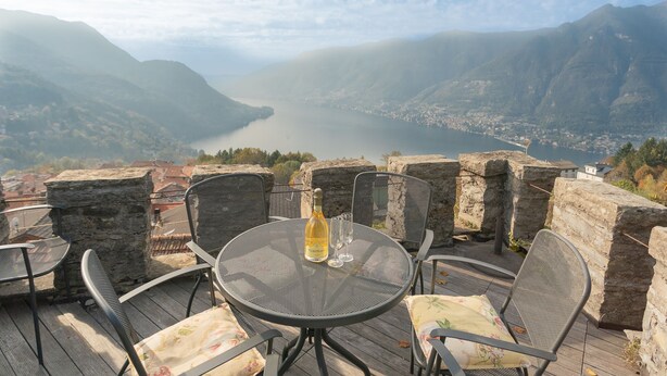 A terrace with a table, chairs, and a bottle of wine, overlooking a valley and a lake. - Co-d462-mpal3at - Villa Sunset Tower (Faggeto Lario)