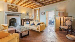A cozy living room with a fireplace, a sofa set, a coffee table, and a dining area with a chair and lamp. - Co-d462-mpal3at - Villa Sunset Tower (Faggeto Lario)