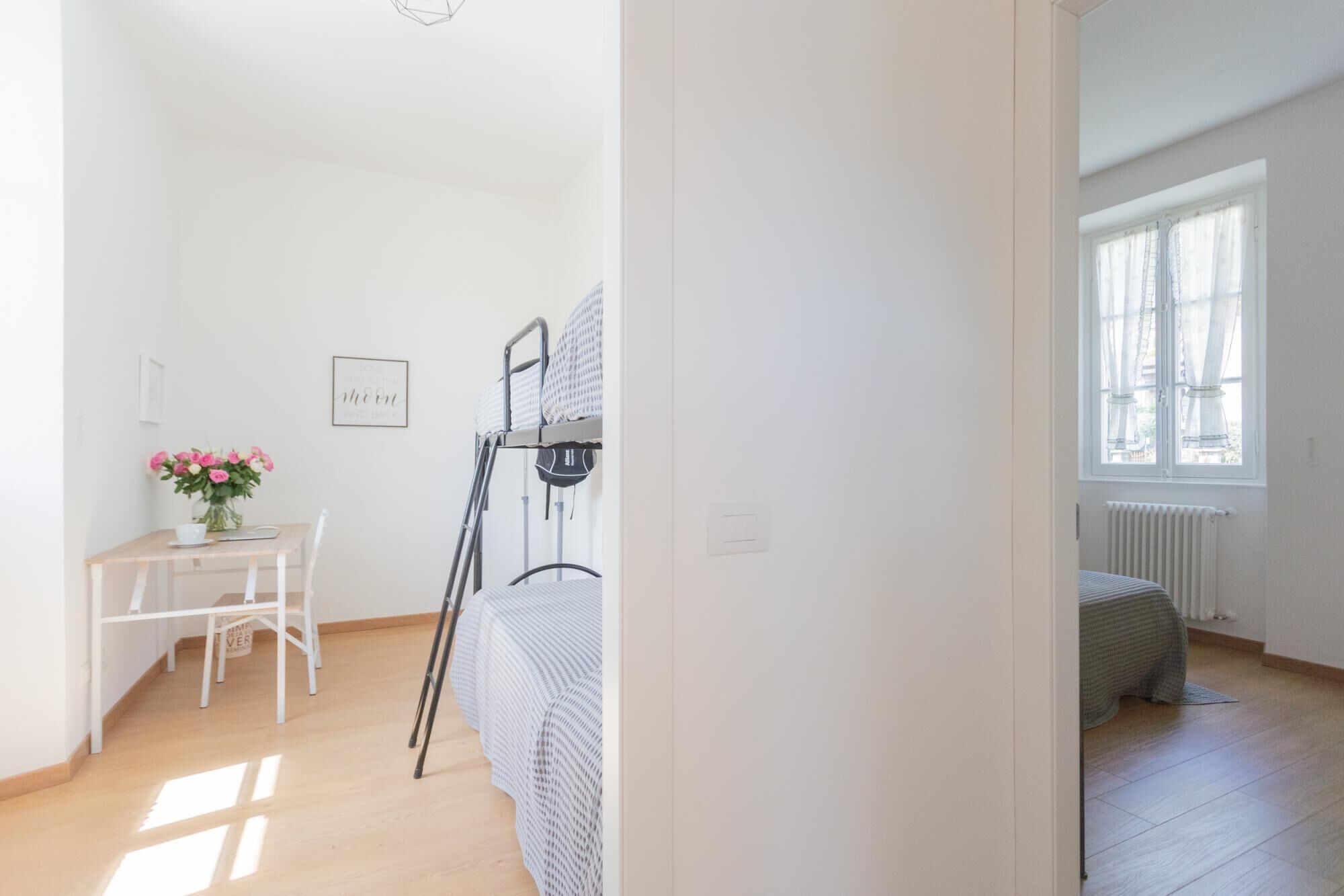 A bedroom with a bed, a desk with a chair, a radiator, and a window.