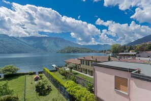 Une propriété au bord du lac, offrant une vue sur les montagnes, avec un quai pour bateaux et un bâtiment doté d’un toit rouge.
