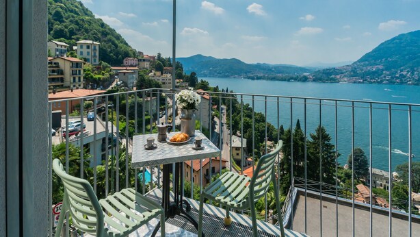 Een balkon met een tafel en stoelen met uitzicht op een meer en stad.