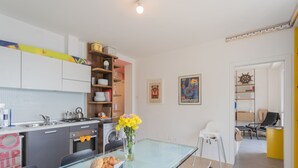 Een moderne keuken met een eethoek, met een glazen tafel, stoelen en een bloevas.