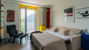 Een moderne slaapkamer met een bed, een stoel, een bureau en uitzicht op de omgeving.