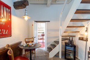 Ein gemütliches Zimmer mit Esstisch, Stuhl, Weinregal und Treppe.