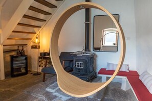 Ein Zimmer mit einer großen, runden Holzschaukel, einem alten Kochherd, einem Spiegel und einer roten Sitzbank.