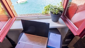 A laptop on a small table with a window view of a boat on water.