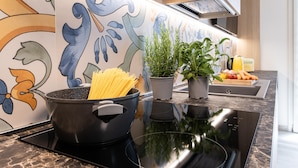 A kitchen with a black stove, pots, and potted plants on the counter.