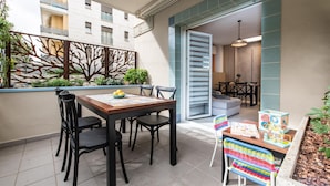 A dining area with a wooden table and chairs, a decorative wall, and a view of a building in the background.