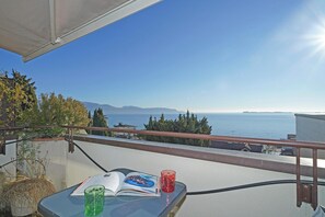 A balcony with a view of the sea, a book, and two glasses on a table. - Appartamento la Vista Bella (Gardone Riviera)