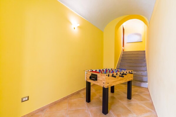 Un pasillo con una mesa de fútbolín de madera y una escalera.