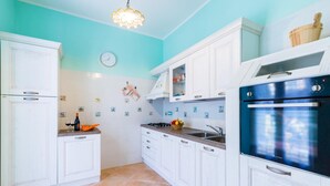 Eine Küche mit weißen Schränken, einem blauen Backofen und einer Uhr an der Wand.