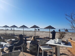 A beachside restaurant with outdoor seating, umbrellas, and a view of the beach and sea. - Casa Le Caravelle in Alghero (Alghero)