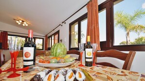 Uma mesa de jantar com frutas diversas, uma garrafa de vinho e um prato de sushi.