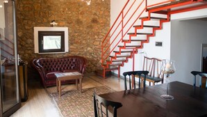 Ein modernes Interieur mit einer Steinwand, einer roten Treppe, einem Ledersofa und einem Essbereich.