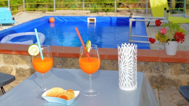A poolside setting with two glasses of orange beverage, a plate of snacks, and a decorative vase. - Al080 Villa Stella Cinese con Piscina Privata (Alcamo)