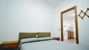 A bedroom with a bed, two nightstands, a wooden door, and a view into a bathroom. - Al080 Villa Stella Cinese con Piscina Privata (Alcamo)