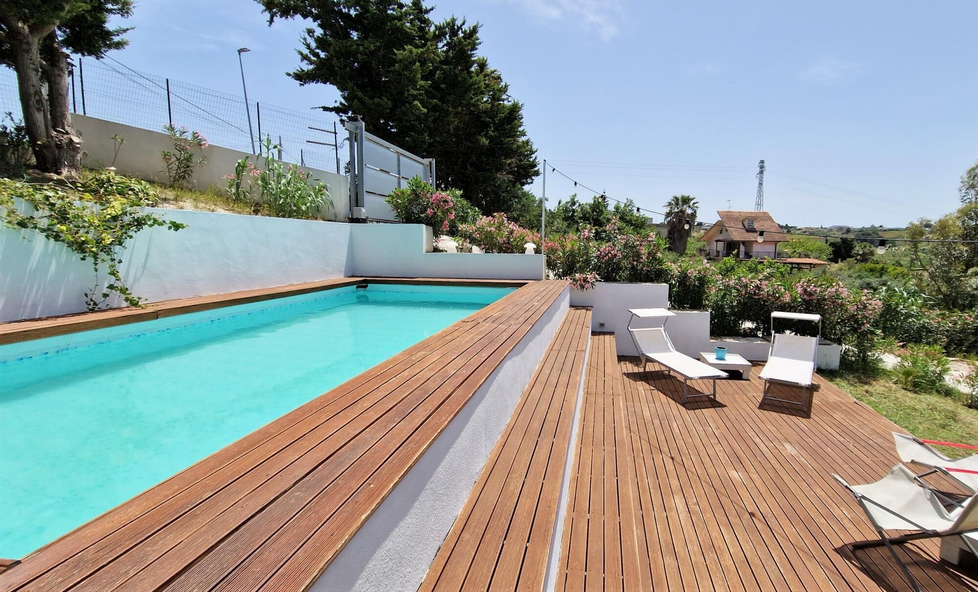 Una piscina con muelle de madera y sillas de descanso.