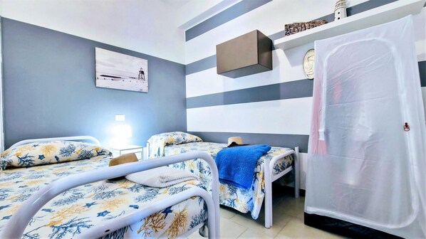 A bedroom with two beds, a bedside table, a lamp, a painting on the wall, and a window with curtains. - Al094 La Piccola Casa di Cinzia (Alcamo)