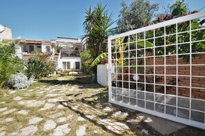 Stroll through the beautifully maintained garden, featuring a variety of plants and a paved pathway, to the two-story building with a balcony.