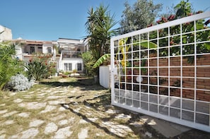 Stroll through the beautifully maintained garden, featuring a variety of plants and a paved pathway, to the two-story building with a balcony.