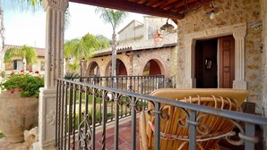 A covered outdoor area with a wrought iron railing, a wicker chair, and a stone wall with arches. - Dependance Desir e Piscina ad uso Esclusivo e Jac (Alcamo)