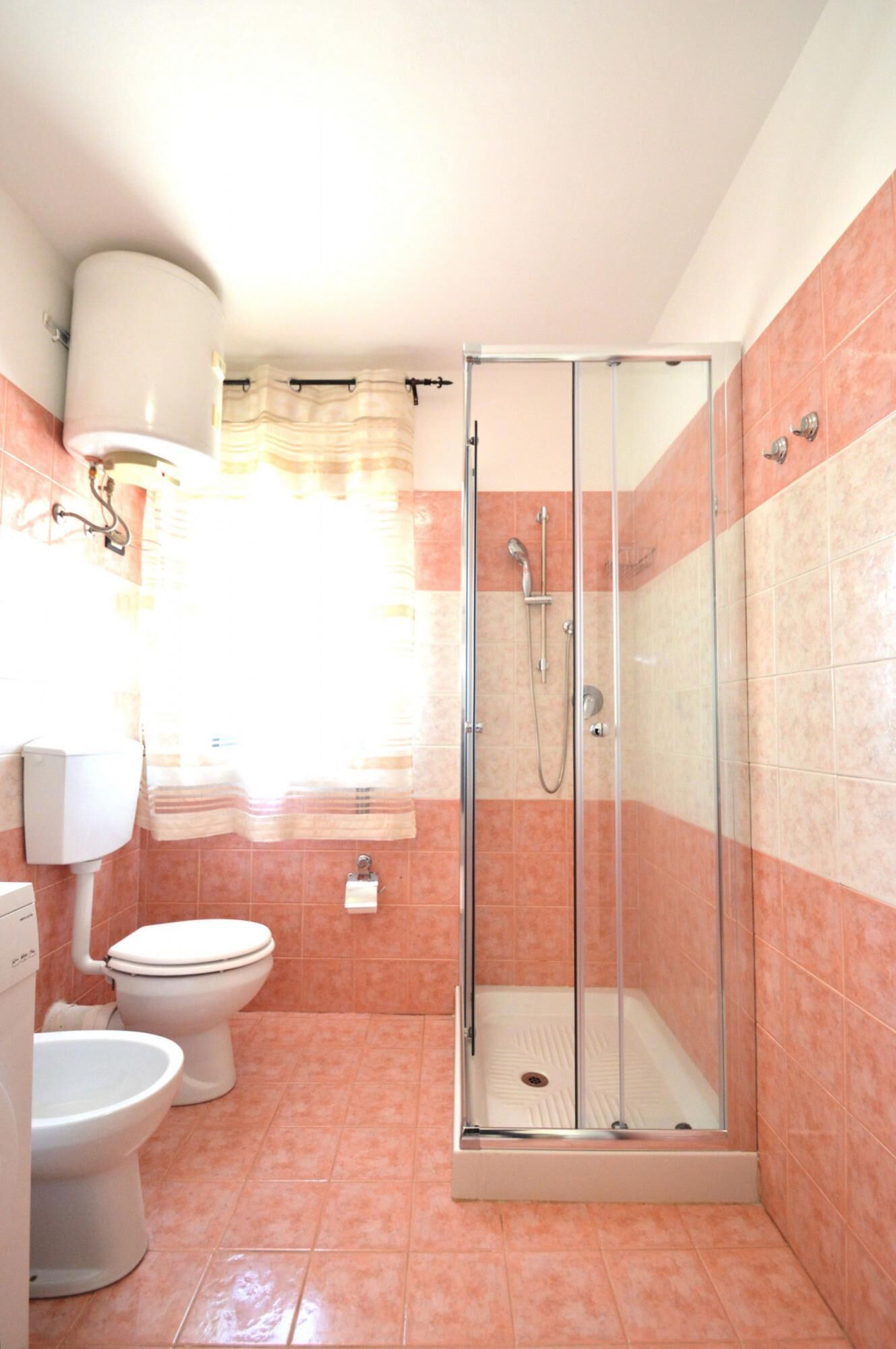 A bathroom with a glass-enclosed shower, two toilets, and a sink.
