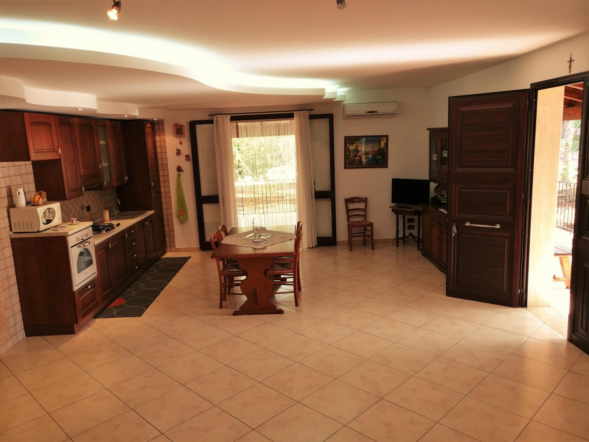 A kitchen with wooden cabinets, a dining table, and a TV.