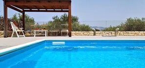 Une piscine avec des chaises longues et une pergola.