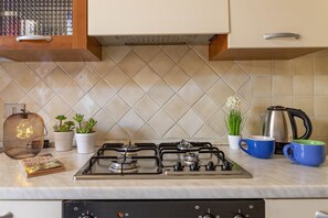 A kitchen with a gas stove, white cabinets, and a tiled backsplash. - Casa Ginestra in Stintino (Stintino)