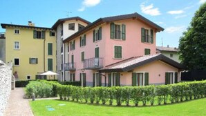 Un edificio residencial de varios pisos con balcones, un césped bien cuidado y un cielo despejado.