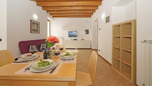 Un comedor con techo de madera, un televisor montado en la pared y un mueble con puertas de vidrio.