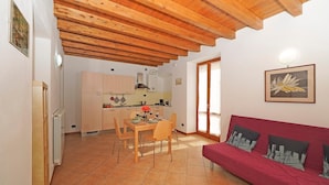 Un espacio habitable compacto con cocina, comedor y un sofá rojo.