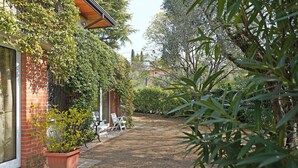 A garden pathway leading to a building with a brick facade and a wooden roof.