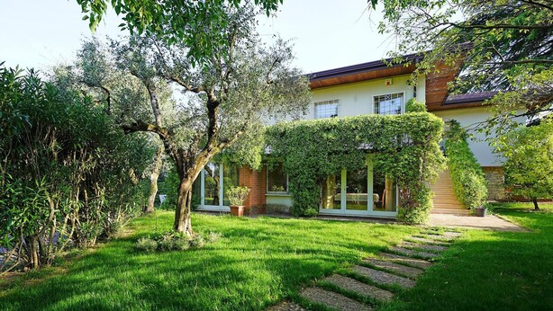 A house with a well-maintained garden, a stone pathway leading to the entrance, and a large window overlooking the garden.