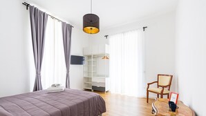 Une chambre à coucher avec un lit, une table en bois, une chaise et un téléviseur fixé au mur.