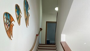 Een trap met houten treden en een leuning, die leidt naar een kamer met een spiegel en een deur.