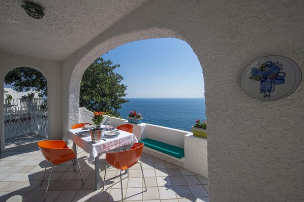 A terrace with a table set for two, overlooking the sea.
