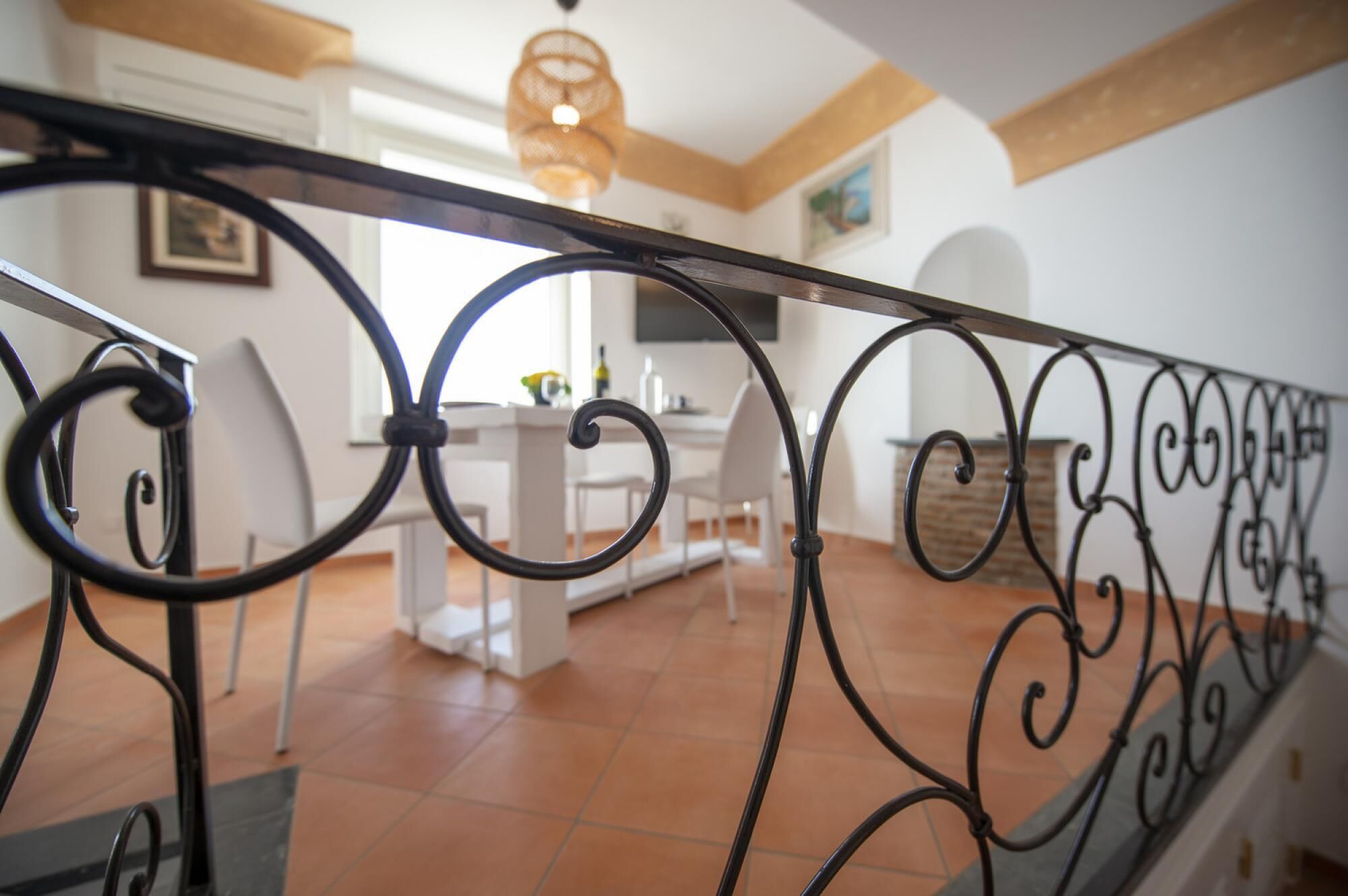 A modern interior with a dining area, white furniture, and a decorative metal railing.