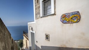 Una calle estrecha con un edificio que tiene una puerta pequeña y una ventana con celosía.