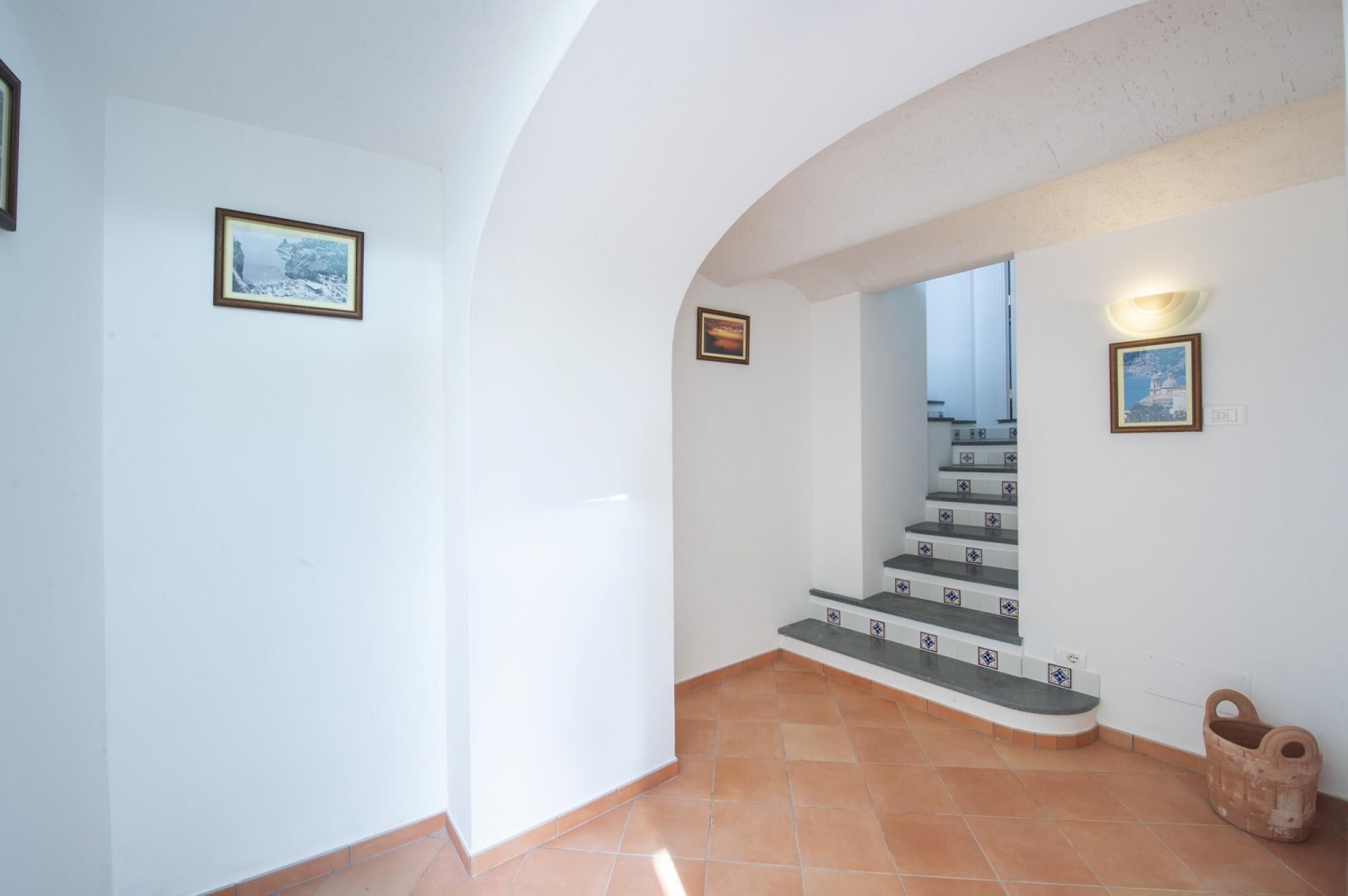 Una escalera con techo curvo y suelo de baldosas que lleva a un nivel superior.