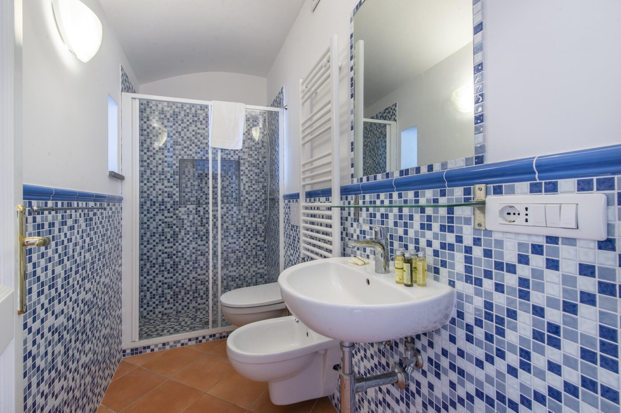 A bathroom with a white sink, a toilet, and a glass shower enclosure.