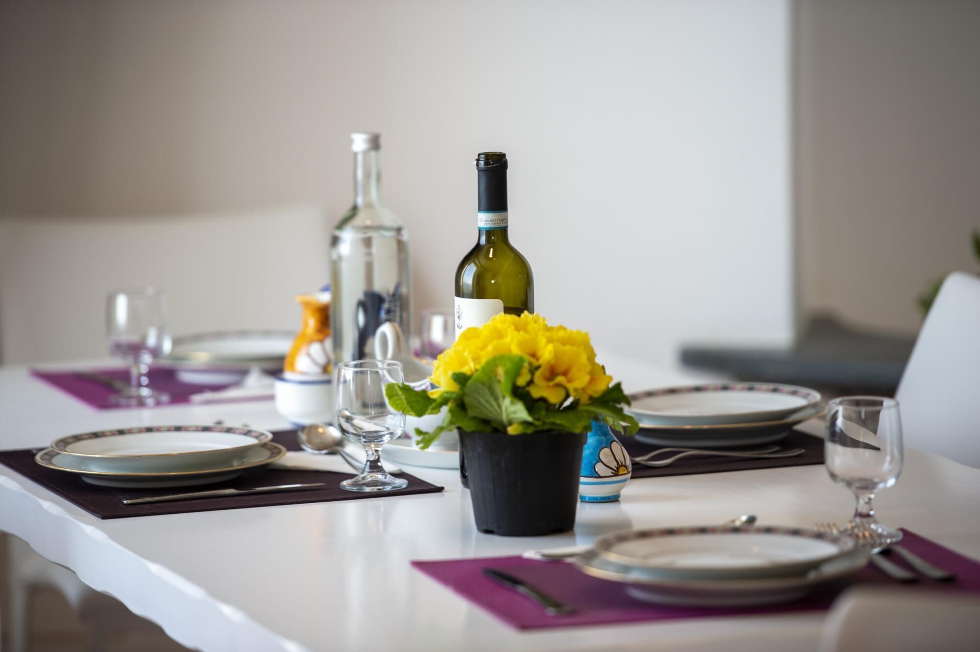 Une table à manger dressée avec des assiettes, des verres et une bouteille de vin.