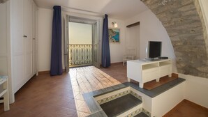 A room with a stone wall, a white cabinet, a TV, and a balcony with a view. - Villa Cimino - Central Villa Stunning Sea View (Praiano)