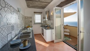 A compact kitchen with patterned tiles, a sink, and a window overlooking the sea. - Villa Cimino - Central Villa Stunning Sea View (Praiano)