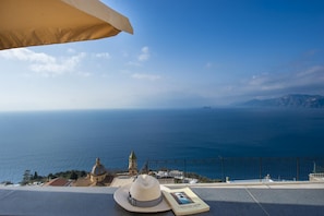 A seaside view with a hat and a book on a table.