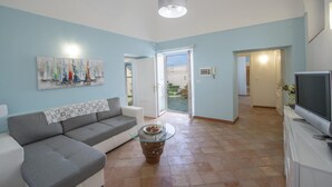 A living room with a sofa, a coffee table, a painting, and a television. - Casa Punta Paradiso - Hot Tub and Panoramic Garden (Praiano)