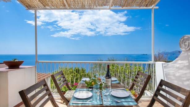 A terrace with a table set for two, overlooking a clear blue sea. - Casa di Nonno Mario - Capri Sunset Views (Praiano)