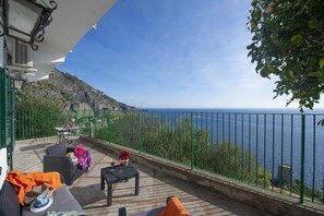 A terrace with outdoor seating, a view of the sea, and a mountainous backdrop. - Casa Cetrangolo - Panoramic House a few Steps From the sea (Praiano)