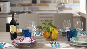 A dining table set with plates, glasses, a wine bottle, and a fruit basket.
