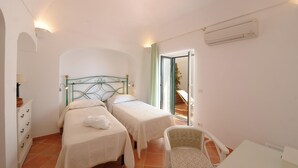 Une chambre avec deux lits, une chaise, un bureau et un appareil de climatisation.